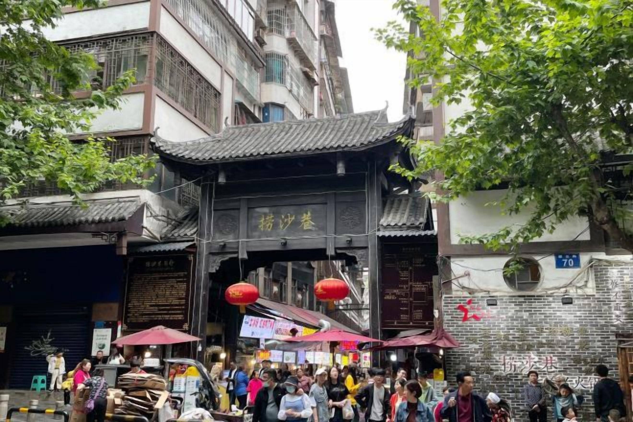 A traditional Chinese gate with a crowd of people and vendors outside.