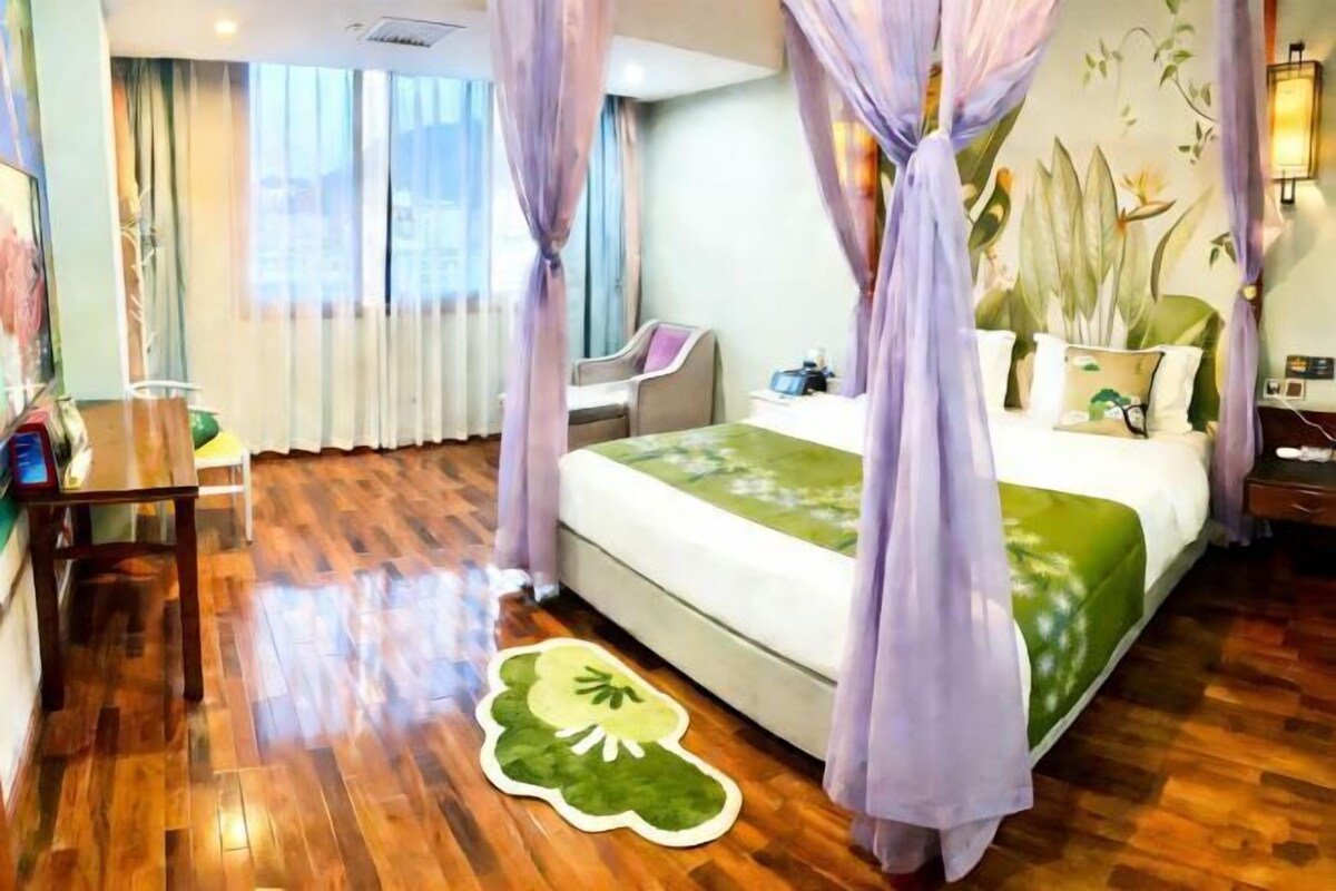 A hotel room with a bed, a desk, a chair, and a large window.