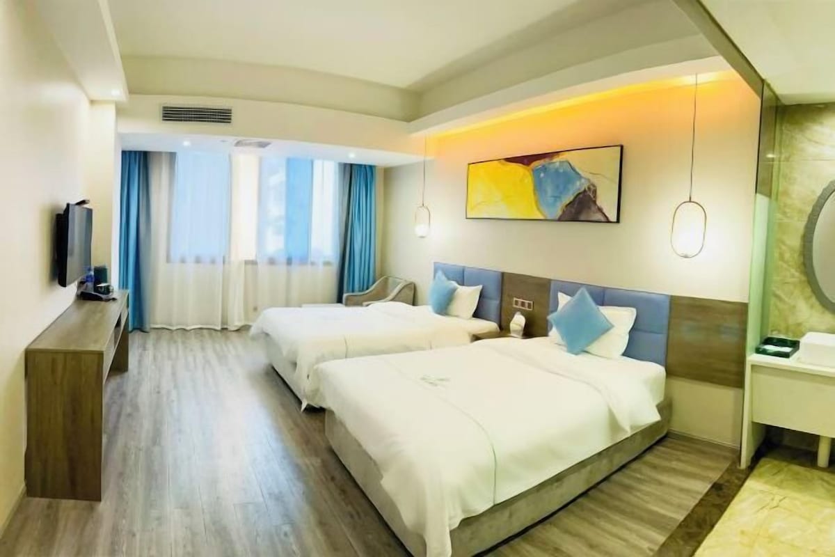 A hotel room with two beds, a TV, a desk, and a bathroom.