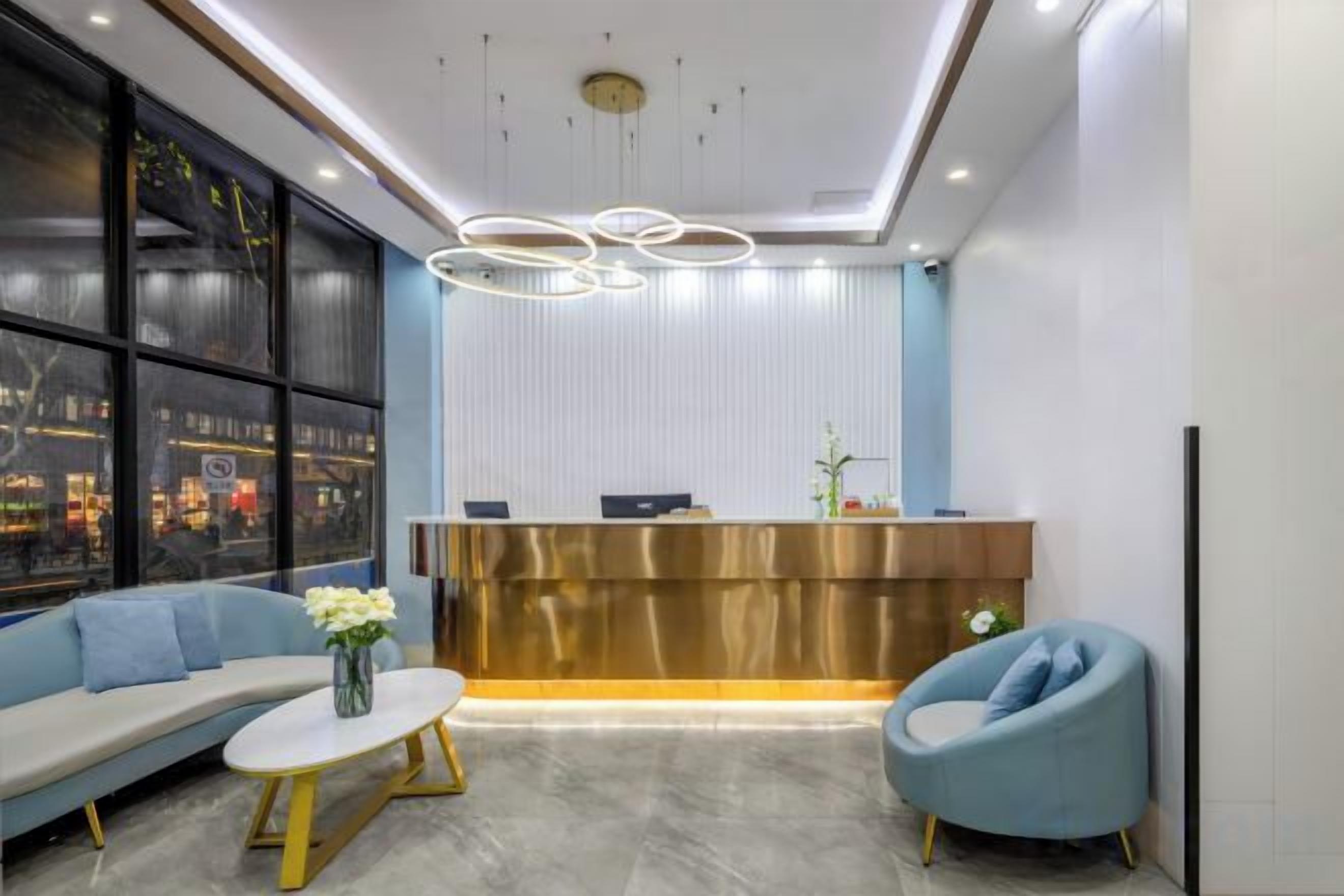 A reception area with a modern design, featuring a reception desk, seating area with sofas and a coffee table, and a large window providing a view.