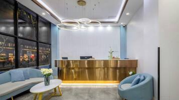 A reception area with a modern design, featuring a reception desk, seating area with sofas and a coffee table, and a large window providing a view.