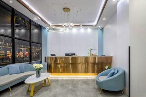 A reception area with a modern design, featuring a reception desk, seating area with sofas and a coffee table, and a large window providing a view. - Biyun Lanting Hotel (Zunyi Huizhi) (Zunyi)