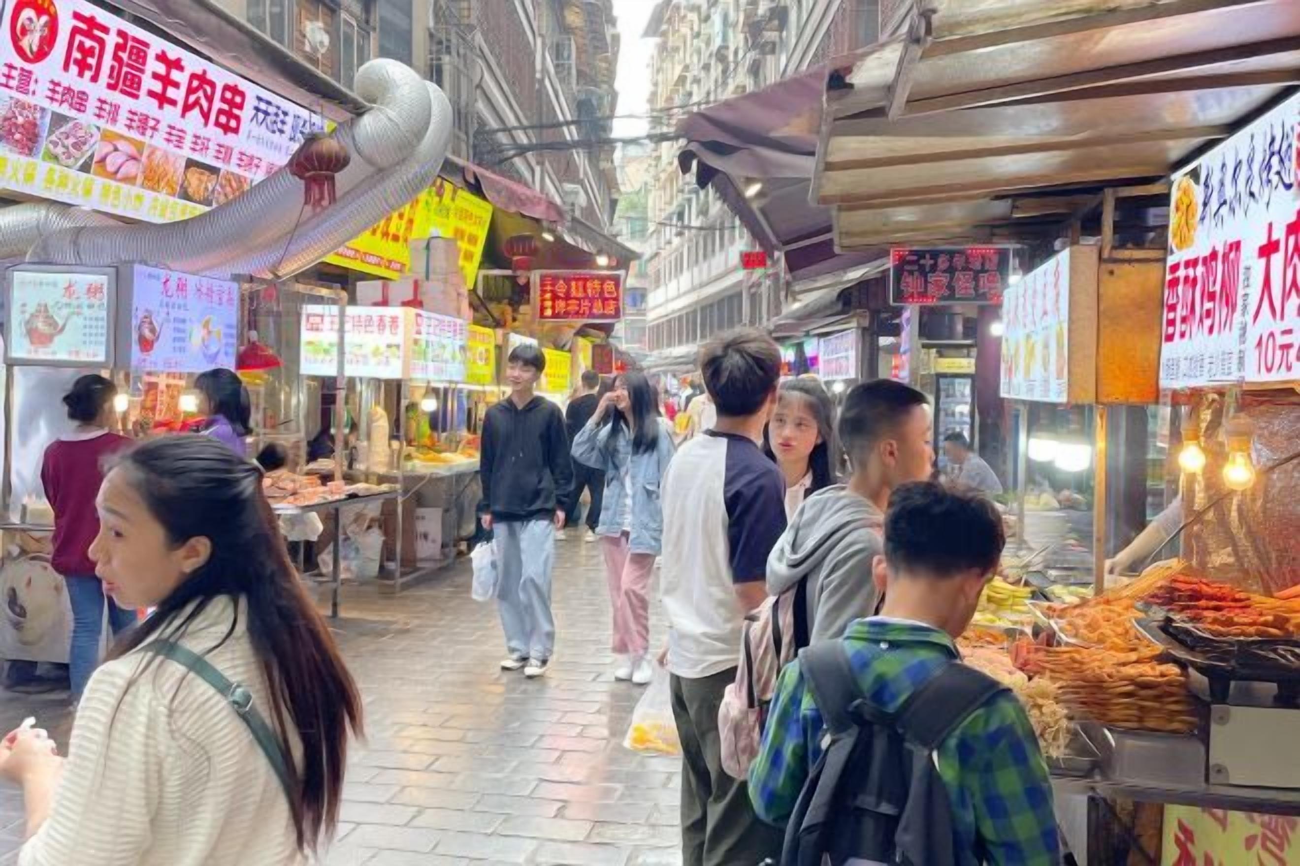 A bustling street market with food stalls and people walking.
