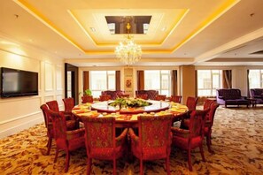 A conference room with a round table, red upholstered chairs, a chandelier, and a flat-screen TV on the wall. - Wantongyuan Pinglu Hotel (Shuozhou)