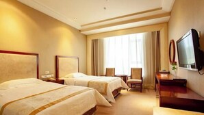 Ein Hotelzimmer mit zwei Betten, einem Fernseher, einem Schreibtisch und einem Stuhl.