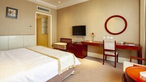 A hotel room with a bed, a desk, a chair, a television, and a mirror.