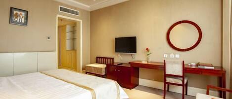 Habitación de hotel con cama, escritorio, silla, televisor y espejo.