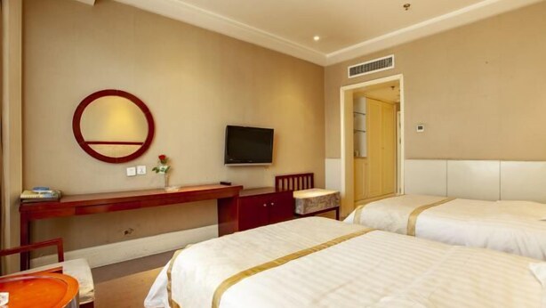A hotel room with two beds, a desk with a TV, a mirror, and a small table with a chair.