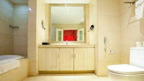 A bathroom with a bathtub, a toilet, a sink with a mirror, and a shower area.