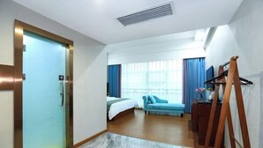 A hotel room with a bed, a sofa, a desk, and a painting easel. - XingheHotel (Chenzhou)