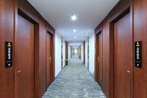 A hotel corridor with wooden doors, numbered room signs, and a marble-patterned floor. - XingheHotel (Chenzhou)