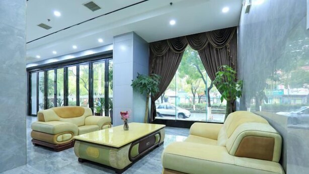 A lobby with two sofas, a coffee table, and large windows with curtains. - XingheHotel (Chenzhou)