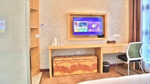 A hotel room with a desk, a television mounted on the wall, a bench, and a chair. - Shaoxing Narnia Garden Hotel (Shaoxing)