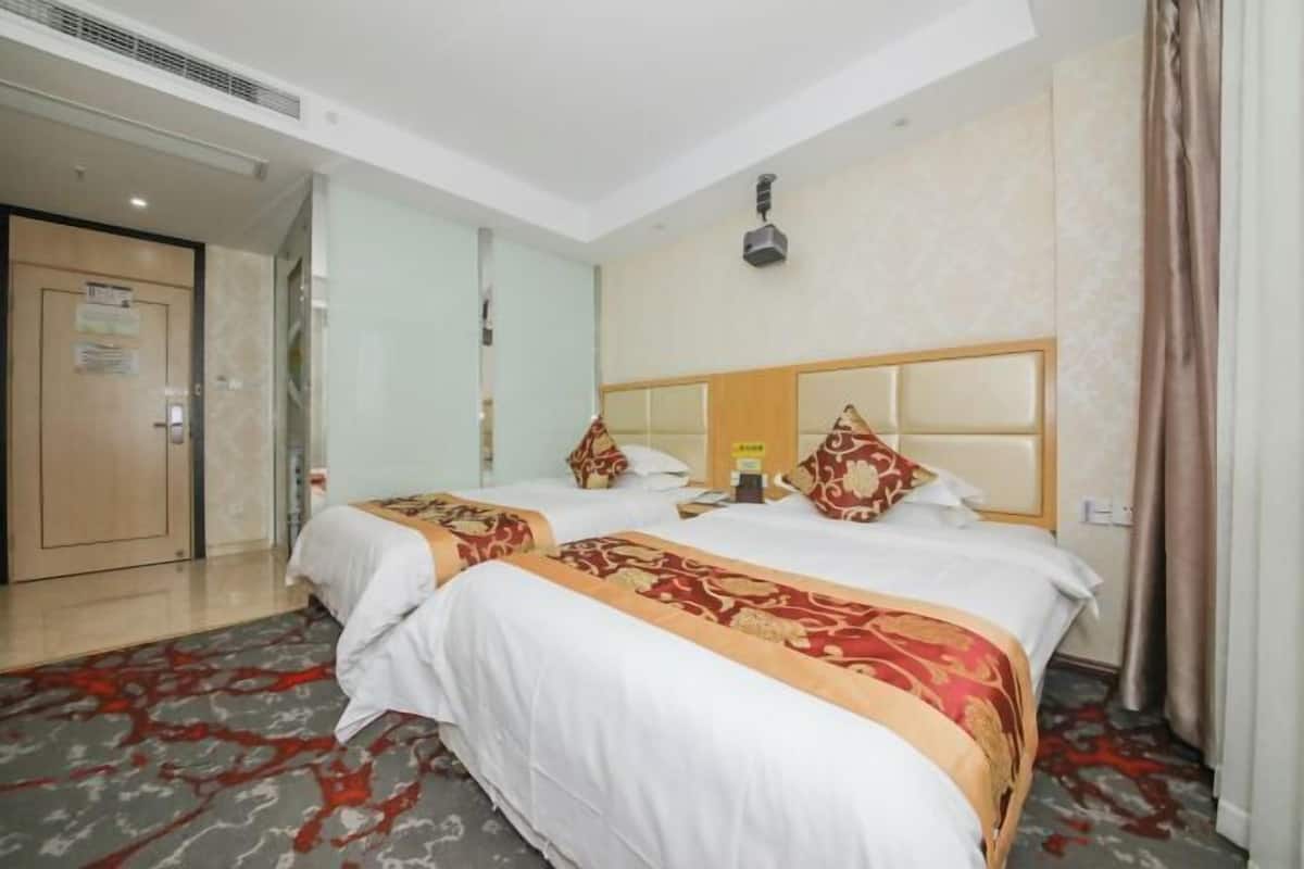 Habitación de hotel con dos camas, un espejo grande, una lámpara del techo y una puerta con un cartel.