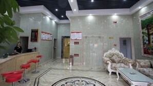 A lobby with a reception desk, red bar stools, a patterned floor, and a sofa. - Shaoxing Narnia Garden Hotel (Shaoxing)