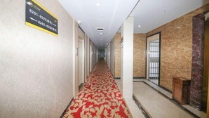 A hotel corridor with a patterned carpet, a reception desk, and a sign with contact information. - Shaoxing Narnia Garden Hotel (Shaoxing)