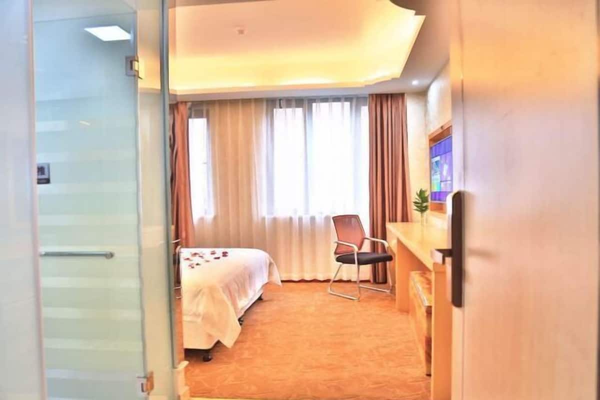Habitación de hotel con cama, escritorio, silla y televisor.