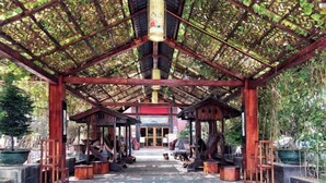 A covered pavilion with a wooden structure, a central column, and a tiled floor. - Shibazi Hotel (Yangjiang)