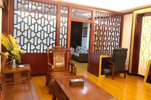 Una habitación tradicional con un separador de madera, un sofá, un escritorio y una silla.