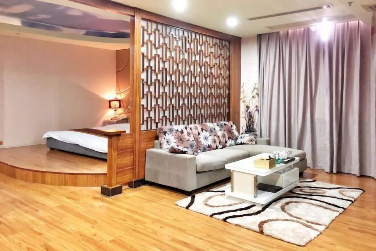 A modern living room with a sofa, coffee table, and a small bed.