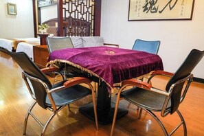 A dining area with a round table covered by a purple tablecloth, surrounded by four chairs with metal frames and cushioned seats. - Shibazi Hotel (Yangjiang)