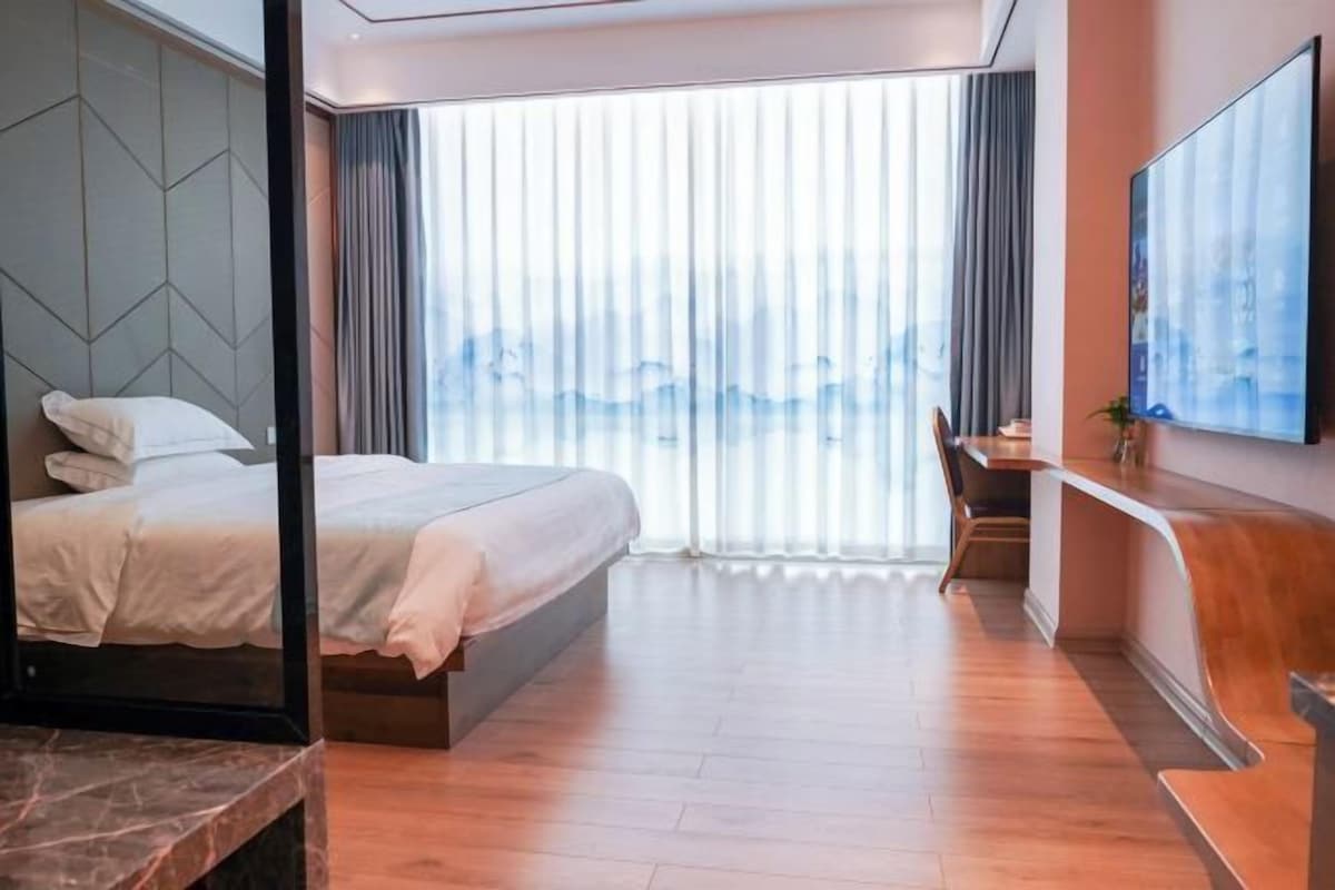 Una habitación de hotel moderna con una cama grande, un escritorio y un televisor.