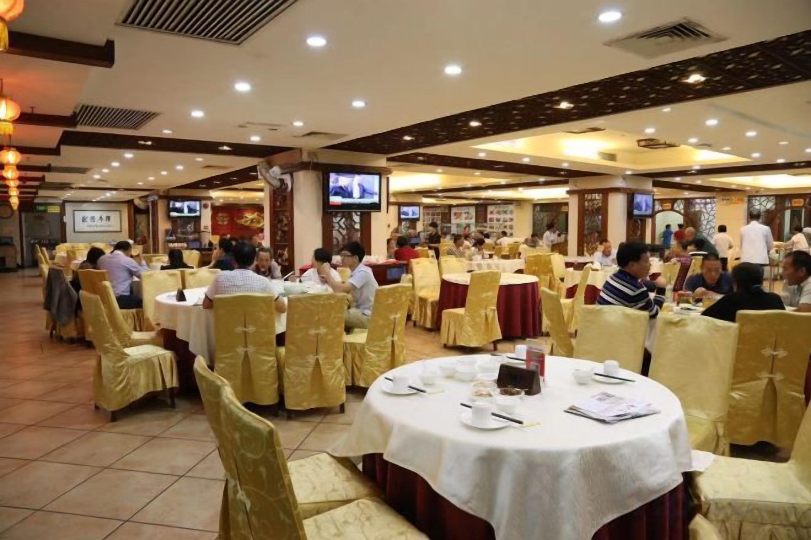 A banquet hall with round tables, chairs, and a tiled floor.