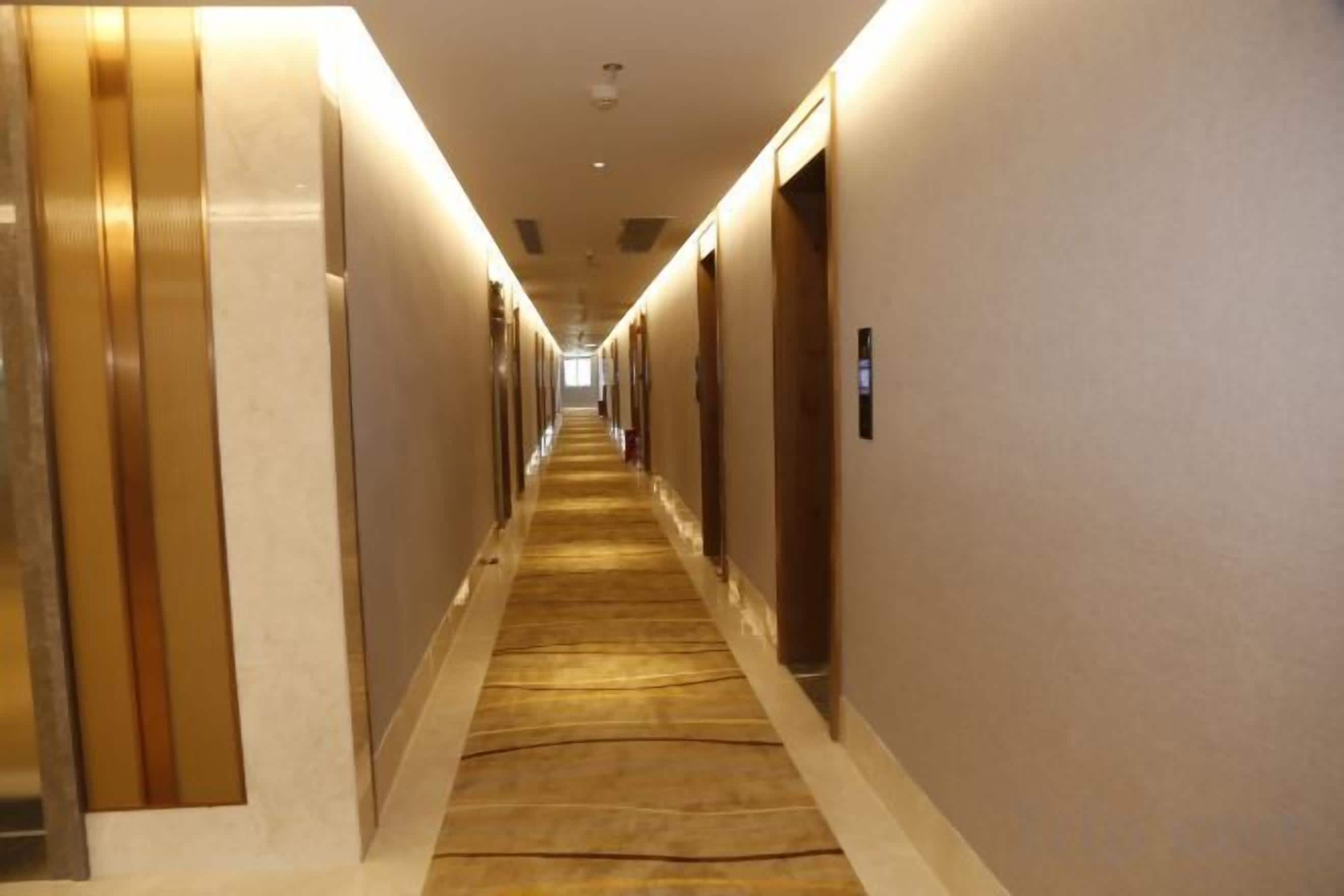Ein Hotelgang mit Teppichböden, Türen an beiden Seiten und einer langen Strecke.