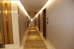 A hotel hallway with carpeted floors, doors on both sides, and a long corridor. - Shibazi Hotel (Yangjiang)