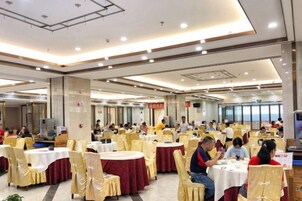 A spacious indoor dining area with round tables and chairs, large windows, and a high ceiling.