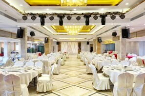A banquet hall with round tables, white chairs, and a central stage. - Shibazi Hotel (Yangjiang)