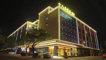A hotel with a prominent sign, multiple floors, and a well-lit facade.