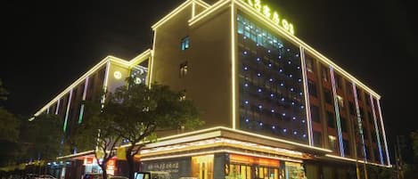 Un hotel con un letrero llamativo, varios pisos y una fachada bien iluminada.
