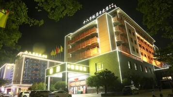 A multi-story hotel with a prominent entrance, multiple balconies, and a well-lit facade.