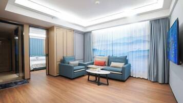 Una habitación de hotel moderna con tragaluces, un conjunto de sofás, una mesa de centro y un gran ventanal con cortinas.