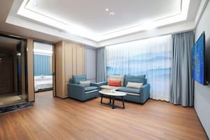 Una habitación de hotel moderna con tragaluces, un conjunto de sofás, una mesa de centro y un gran ventanal con cortinas.