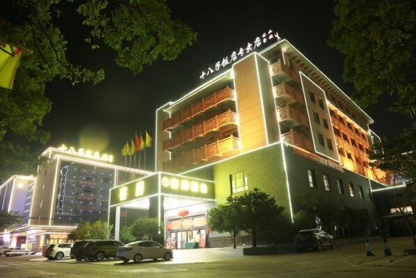Ein mehrstöckiges Hotel mit einem gut beleuchteten Eingang und mehreren Balkonen.