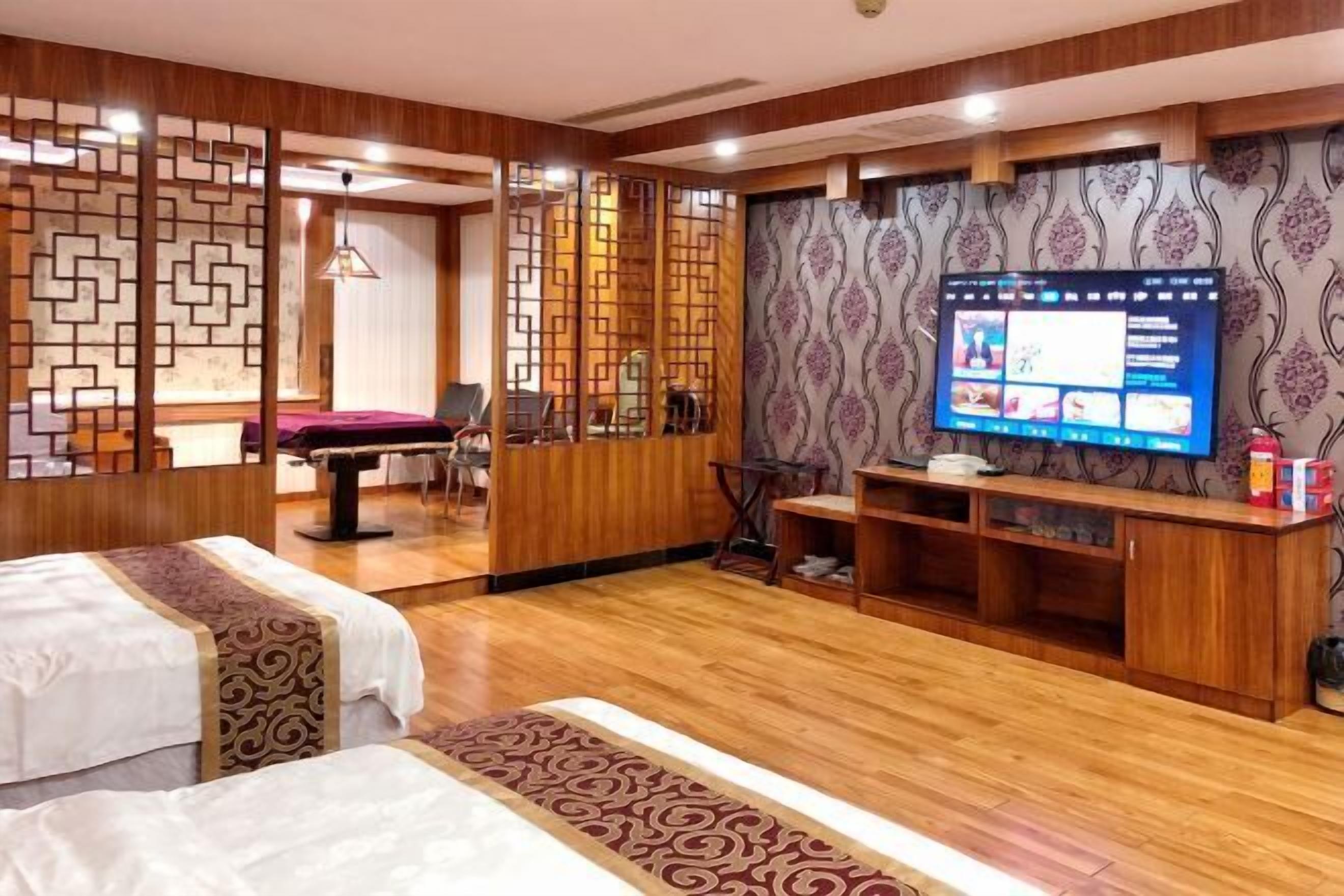 Habitación de hotel con dos camas, televisión, separador de madera y mesa de billar.