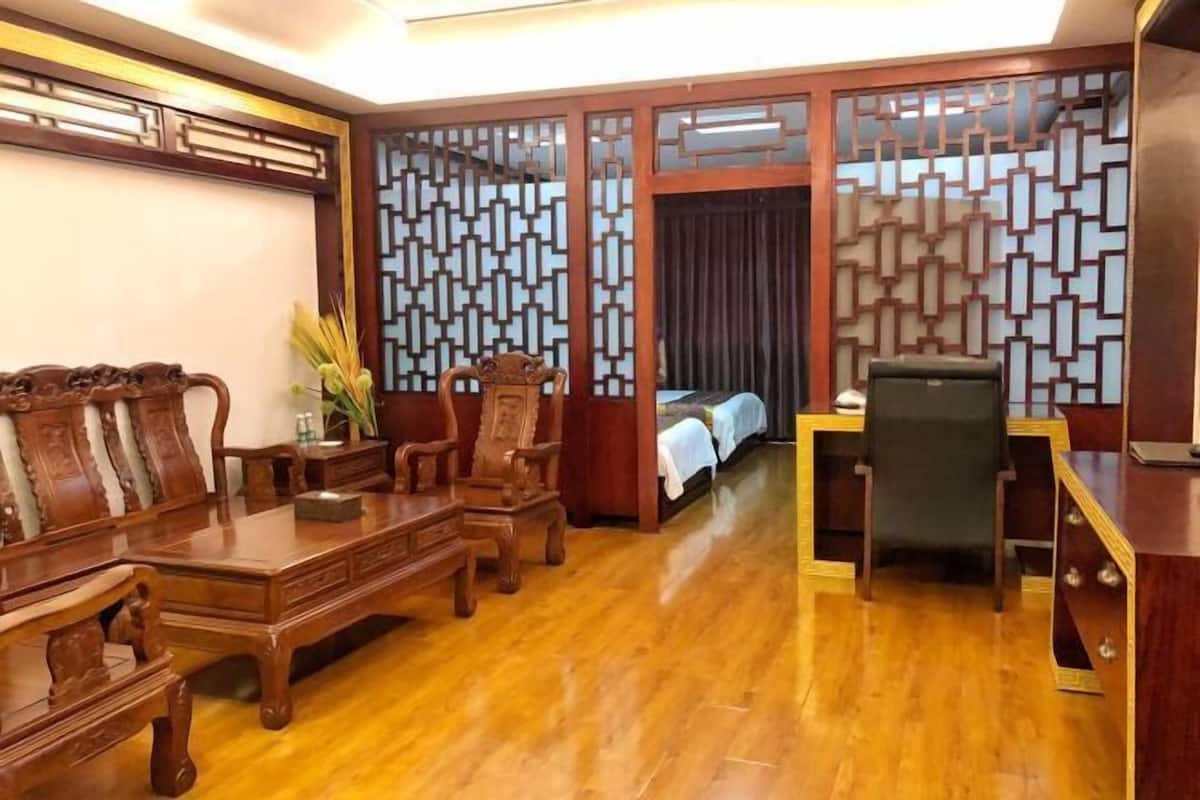 A traditional wooden room with a dining table, chairs, a desk, and a bed.