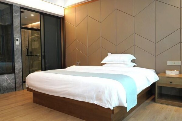 A modern hotel room with a large bed, a glass shower enclosure, and a wooden nightstand. - Shibazi Hotel (Yangjiang)