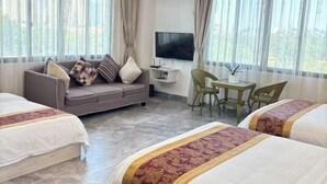 A hotel room with a sofa, two beds, a TV, and a table. - Tangquan Mingwu Hostel (Xiamen)