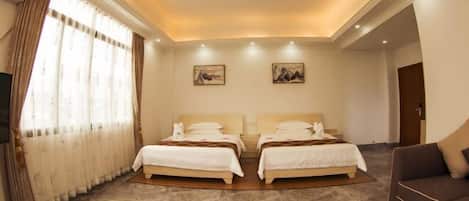 Une chambre d’hôtel avec deux lits, un canapé, une télévision et des œuvres d’art accrochées aux murs.