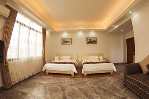 A hotel room with two beds, a sofa, a TV, and artwork on the walls. - Tangquan Mingwu Hostel (Xiamen)