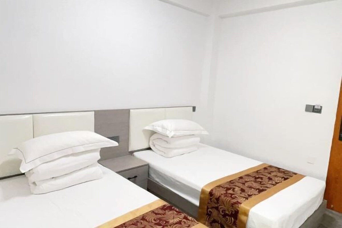 A hotel room with two beds, a nightstand, and a wooden door.