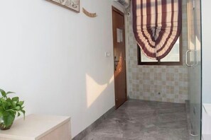 A hallway with a tiled floor, a potted plant, and a door with a striped curtain. - Tangquan Mingwu Hostel (Xiamen)