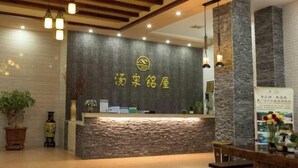 A reception area with a stone counter, wooden ceiling beams, and hanging pendant lights. - Tangquan Mingwu Hostel (Xiamen)