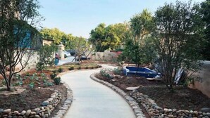 A pathway leading through a landscaped garden with a variety of plants and trees. - Tangquan Mingwu Hostel (Xiamen)