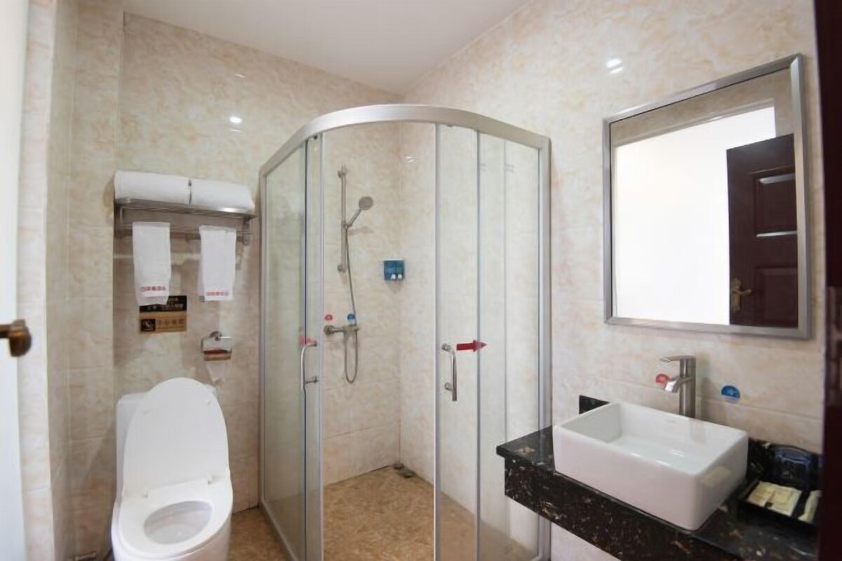 A modern bathroom with a glass-enclosed shower, a white toilet, and a sink with a black countertop.