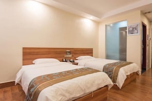 A hotel room with two beds, wooden headboards, and a nightstand with a clock.