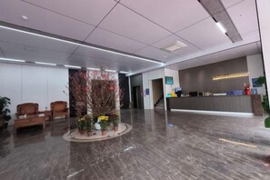 Un lobby moderno con una recepción, una zona de estar y un arreglo decorativo de plantas.